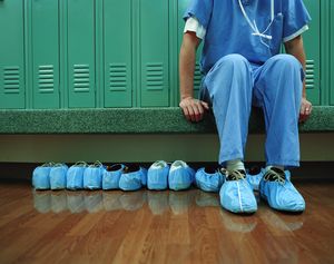 Medical worker wearing overshoes in locker room, low section