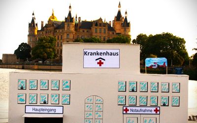 Ein etwa 1,5 m³ großes Krankenhausmodell wurde symbolisch vor der Kulisse des Schweriner Schlosses versenkt